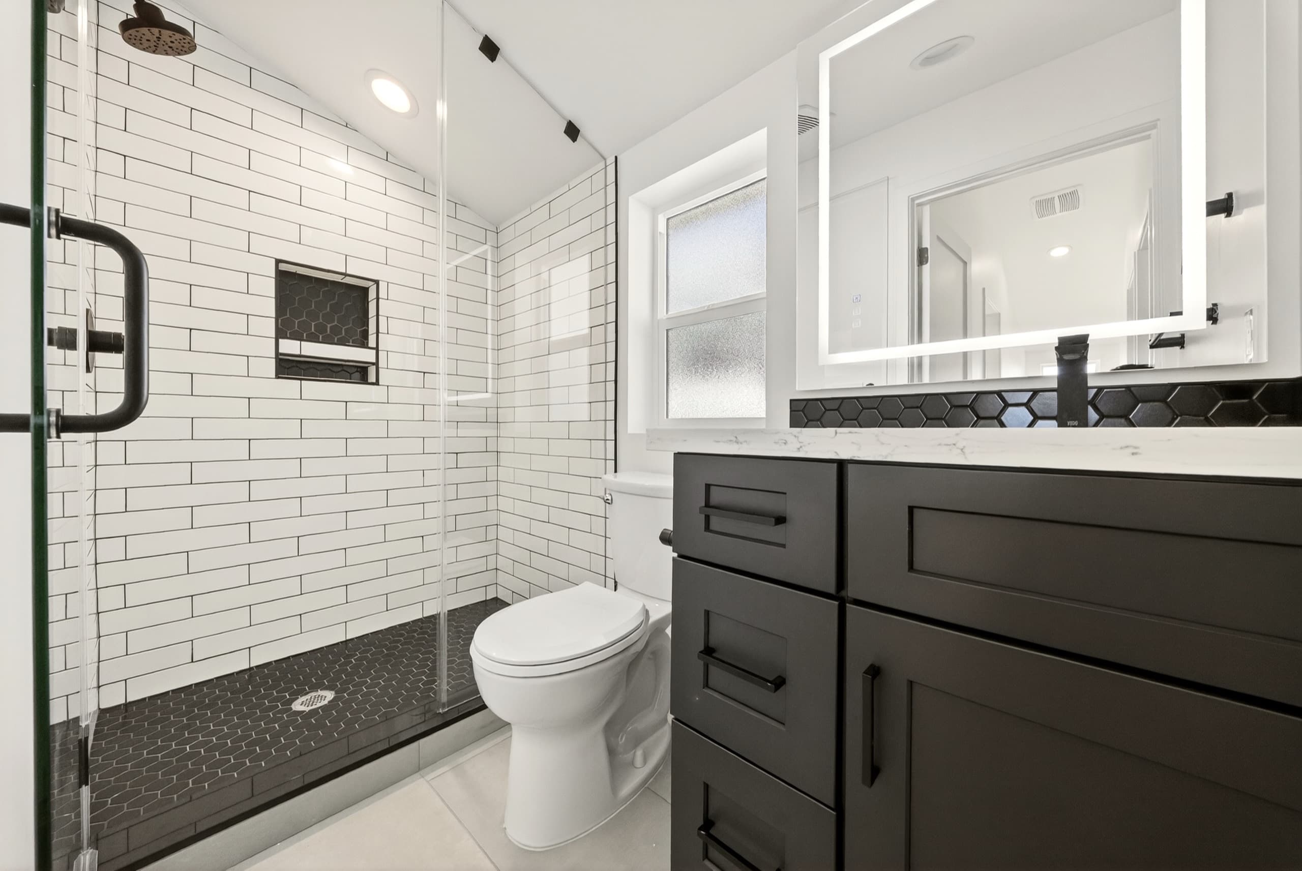 Unit bathroom with subway tile and dark vanity